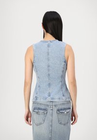 Denim mouwloos topje in lichtblauw met een strakke pasvorm, met zichtbare stiksels en een ronde halslijn. De rug is recht gesneden.