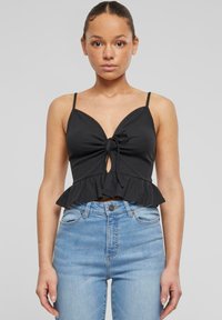 Černý žebrovaný crop top s peplum spodn�ím lemem, přední šňůrkou a tenkými ramínky. Kombinováno se světle modrými vysokými džíny.