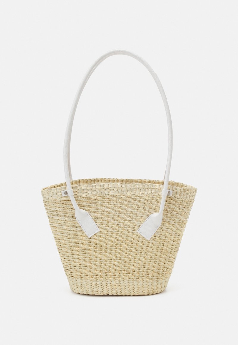 Sac à main en paille tressée avec un fond plat et des bretelles d’épaule hautes, fines et blanches fixées des deux côtés.