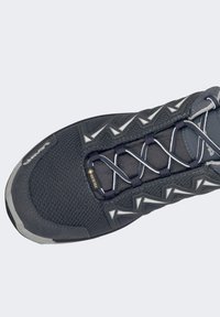 Grijze wandelschoen met een textiel bovenwerk, voorzien van een GORE-TEX label, reflecterende accenten en een minimalistisch vetersysteem.