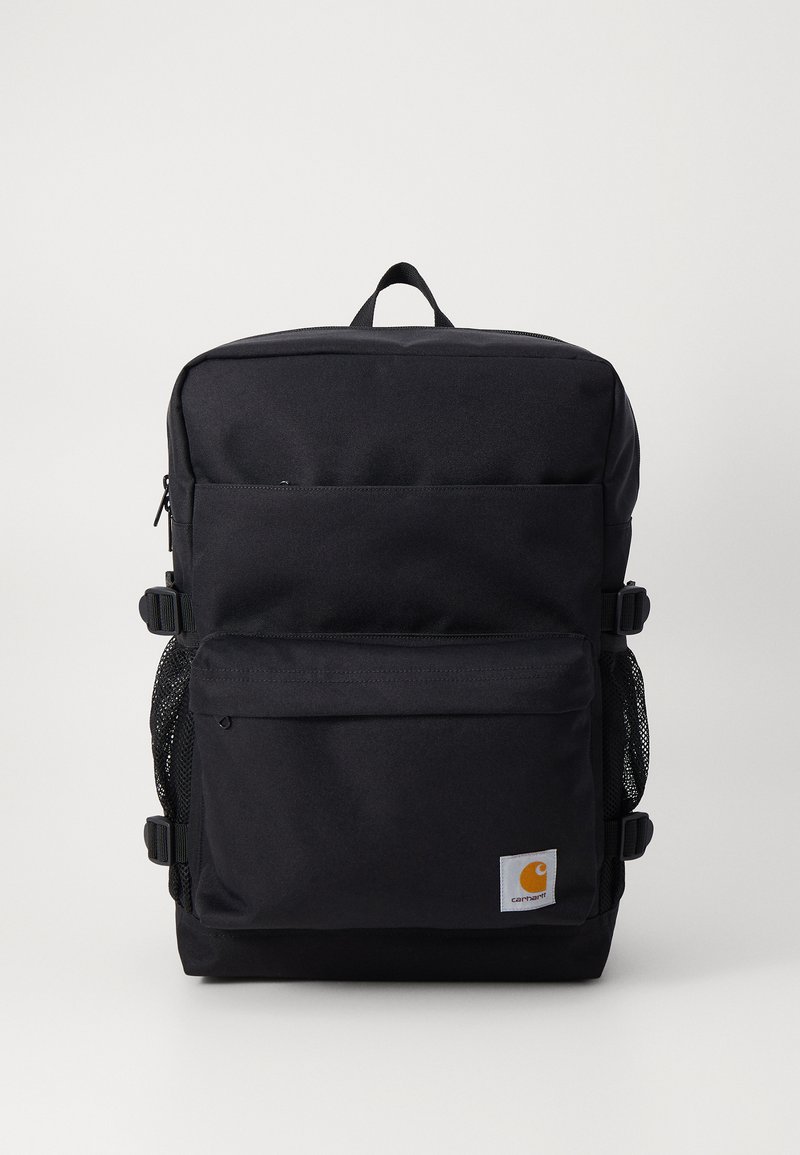 Mochila negra hecha de tela duradera, con dos bolsillos frontales con cremallera, bolsillos de malla en los laterales y una asa de transporte en la parte superior. Logo de la marca en el frente.