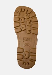Suola di scarpe in gomma marrone con profondi modelli di battistrada. Presenta il logo "CAMPER" e la taglia "42". Superficie testurizzata con una combinazione di aree lisce e strutturate.