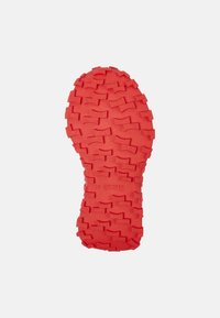 Semelle en caoutchouc rouge avec un motif de grip texturé, comprenant des indentations et des sections surélevées, marquée du logo '28 CAMPER'.