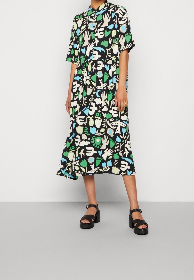Robe midi noire ornée de motifs vibrants de mains, de fleurs et d'abstraits en vert, bleu et blanc ; manches courtes et fermeture à boutons.