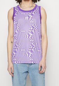 Lila linne med ett vågigt vitt och lila mönster, med en ribbad halsringning och ärmhål. Odekorerad tyg, avslappnad passform.