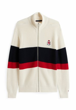 Cardigan en tricot à zip de couleur crème avec des rayures horizontales bleu marine, rouge et blanche. Il présente une texture côtelée et un logo brodé sur la poitrine.