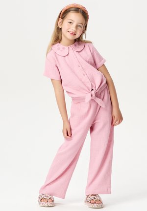 Ensemble rose en deux pièces comprenant un haut à manches courtes avec des boutons, un col et une ceinture à nouer, associé à un pantalon à jambes larges en tissu texturé.