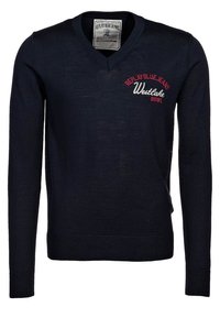 Marinblå v-ringad tröja i stickat tyg, med vit och röd textbroderi på bröstet samt ribbad nederkant och ärmslut.