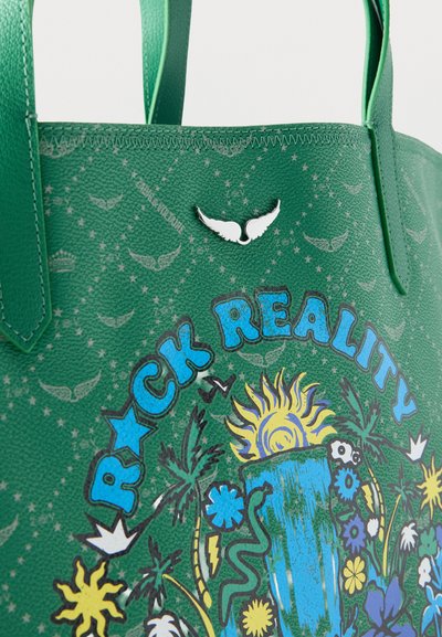 Πράσινη τσάντα tote με πολύχρωμο σχέδιο ήλιου, φυτών και λουλουδιών, μπλε κείμενο "Rock Reality" και λευκό μεταλλικό έμβλημα σε σχήμα φτερού κοντά στην άνω άκρη.