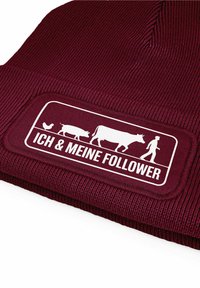 Maroon beanie with ribbed texture. Features a white rectangular patch displaying farm animals and text "ICH & MEINE FOLLOWER."