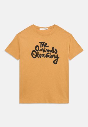 T-shirt jaune moutarde à manches courtes avec texte manuscrit noir "The Animals Observatory" au centre devant.