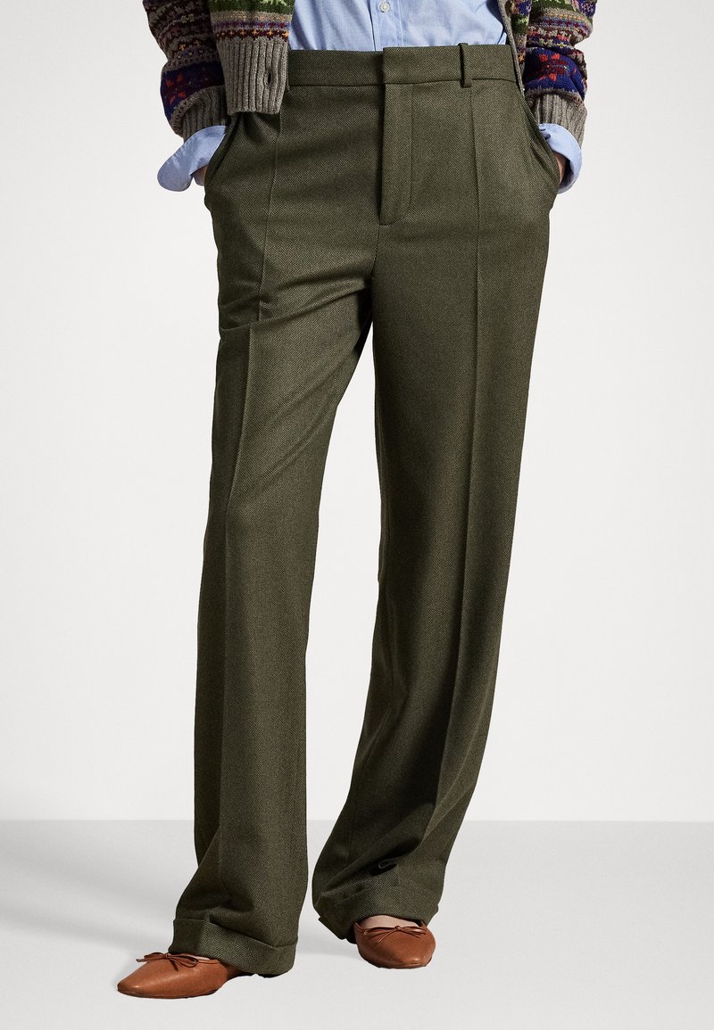 Pantalon taillé vert olive avec une coupe ample, devant plissé et poches latérales. Le matériau présente une texture subtile adaptée à une tenue formelle.