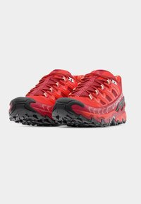 Κόκκινα αθλητικά παπούτσια με υφασμάτινο άνω μέρος με υφή, έντονο σύστημα κορδονιών και παχιά μαύρη εξωτερική σόλα από καουτσούκ με ανθεκτικά πέλματα.