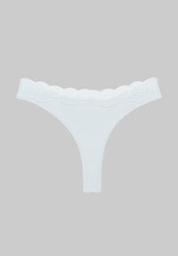 Λευκό στρινγκ εσώρουχο με δαντέλα, απλωμένο επίπεδα σε γκρίζο φόντο.