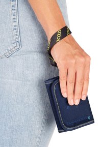 Navy blue wallet made of durable fabric, featuring yellow stitching and a black wrist strap with green logo accents. Compact design for easy handling.