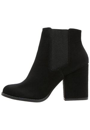 Mustat mokkanahka nilkkurit, joissa on paksu korko, joustavat sivupaneelit ja pyöristetty kärki. Sujuva pinta ja ommeltuja yksityiskohtia pohjan ympärillä.