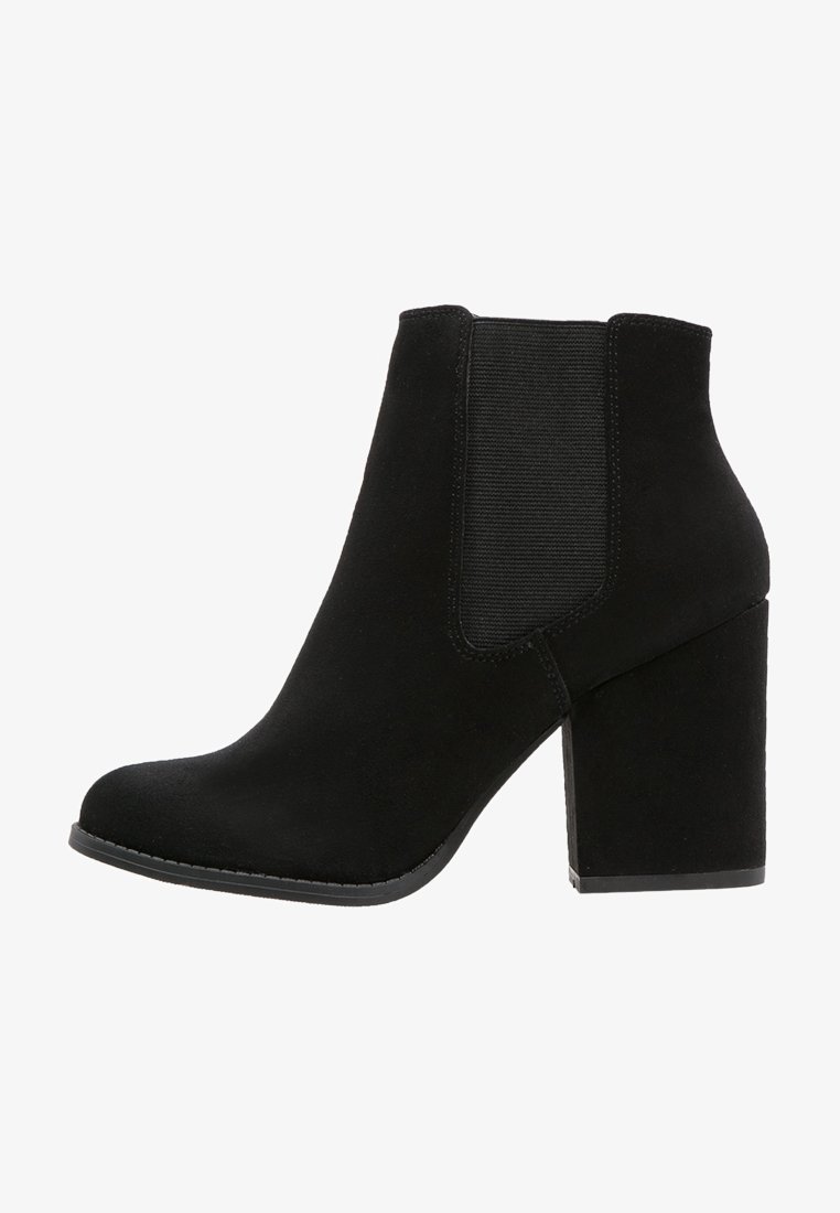 Bottines noires en daim avec un talon épais, des panneaux latéraux élastiques et un bout arrondi. Texture lisse avec des accents cousus le long de la semelle.