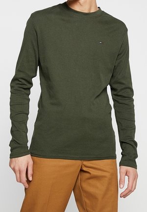 Halenka s dlouhým rukávem v olivově zelené barvě vyrobená z bavlny, s kulatým výstřihem a malou nášivkou s logem na hrudi. Hladká textura.