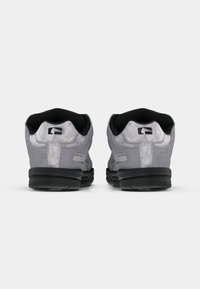 Pair of grey athletic shoes with black soles and padded black inner lining, viewed from the back on a plain white background.