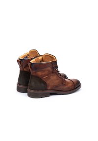 Botas de tobillo de cuero marrón con paneles texturizados, punteras redondas y diseño de cordones. Cuenta con un forro marrón claro y una suela de goma resistente.