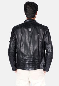 Czarna skórzana kurtka motocyklowa z pikowanymi detalami na ramionach i dolnej części pleców, naszywka marki na górnej części pleców oraz dopasowany fason.