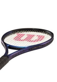 Raqueta de tenis con un marco negro y morado, cuerdas blancas y un logo rojo. Presenta un agarre texturizado y un diseño aerodinámico.