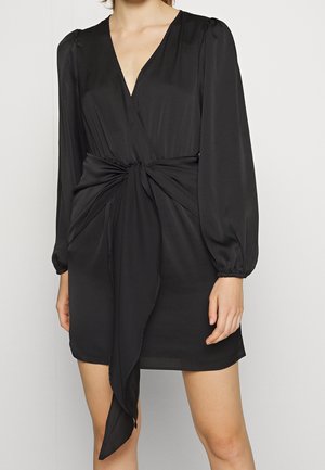 Schwarzes Wickelkleid mit langen Puffärmeln, tiefem V-Ausschnitt und Knoten-Detail an der Taille. Hergestellt aus glattem, leichtem Stoff.