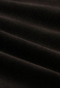 Textureret sort stof med ribbet mønster, der fremhæver en blød følelse og en subtil glans fra foldede lag, der skaber dybde og dimension.