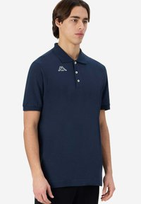 Polo shirt blu navy a maniche corte con colletto a ribattino, patta con tre bottoni e logo bianco accentato. Materiale in cotone morbido con un design semplice.