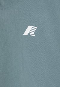 Lichtblauw stoffen t-shirt met een ronde halslijn, voorzien van een wit grafisch logo aan de linkerzijde. Gladde textuur en casual ontwerp.