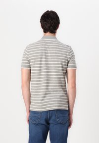 Γκρίζο polo μπλουζάκι με ρίγες και κοντά μανίκια, που διαθέτει λευκές ορ�ιζόντιες ρίγες, γιακά και ευθεία τελειώματα. Φοριέται με μπλε τζιν παντελόνι.