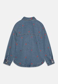 Denimskjorte med krage, prydet med røde jordbærbroderier over hele skjorten og med knappede mansjetter. Lyseblåt stoff med klassisk snitt.