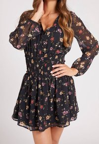 Schwarzes Blumenkleid mit langen Ärmeln, gerafft an der Taille und ausgestelltem Rock; verfügt über bunte Blumenmuster auf transparentem Stoff.