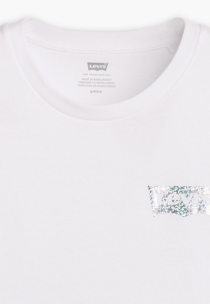 T-shirt blanc à manches courtes avec un logo Levi's pailleté en design bleu clair et argent. Fabriqué en coton doux.