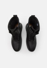 Svarta läderankelboots med en slät yta, rund tå, snörning fram och sidodragkedja. Fodret är mjukt med en brun innersula.