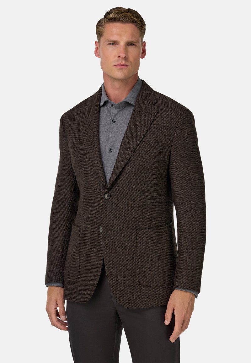 Brązowa blazer z fakturowanej tkaniny, z klapami, dwoma przednimi kieszeniami i zapięciem na jeden guzik, nałożona na szary koszulę.