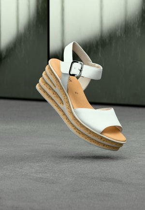 Sandale blanche à talon compensé ouvert avec tige texturée, bride de cheville réglable et semelle plateforme superposée imitation liège. Finition en cuir lisse.