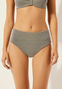 Kalhotky bikiny s vysokým pasem s černo-b�ílými vertikálními pruhy, vyrobené z texturované látky, s hladkým pasem a umírněným střihem.