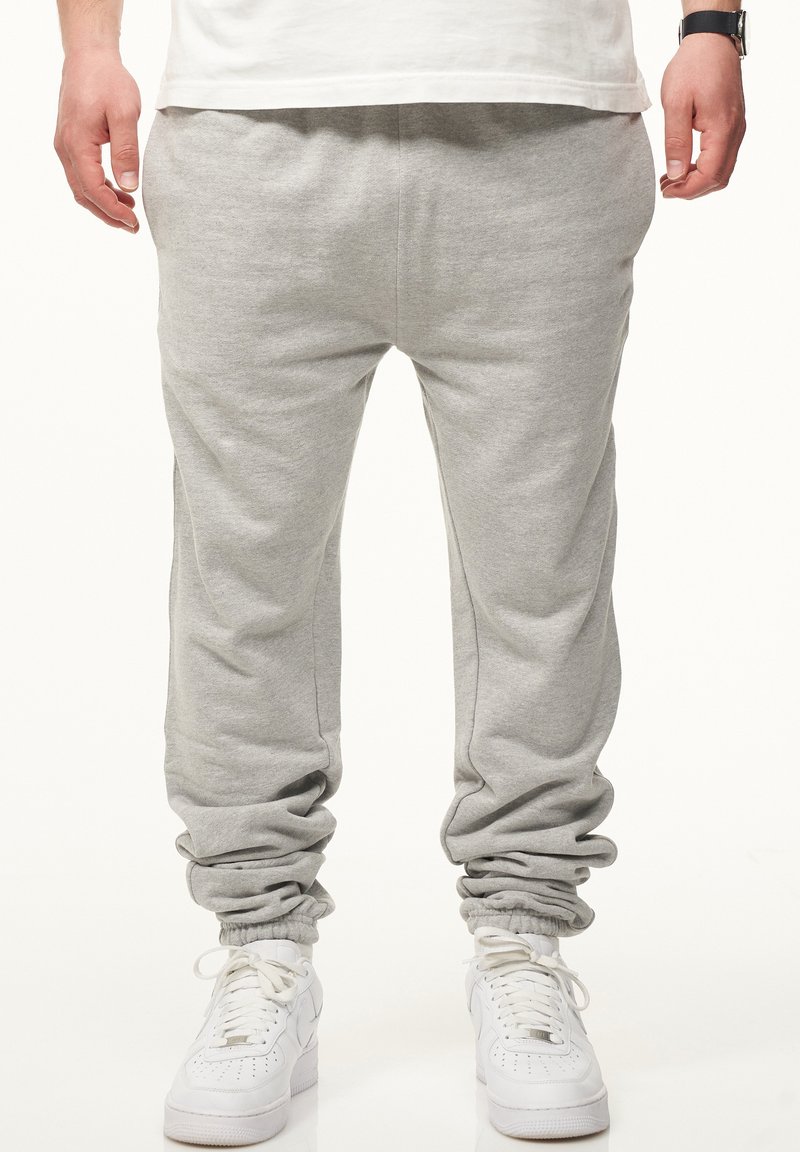 Graue Jogginghose aus weichem Stoff, mit elastischen Bündchen an den Knöcheln und einem lässigen Schnitt. Kombiniert mit weißen Sneakers.