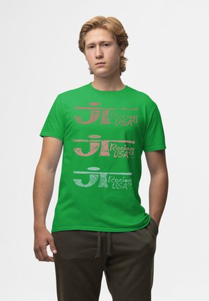 Grøn bomulds t-shirt med trykt tekst i pink, hvid og sort med et racingmotiv. Korte ærmer og klassisk pasform.