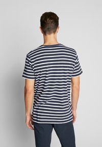 Marineblå og hvide stribet t-shirt med korte ærmer, rund hals og almindelig pasform. Bomuldsmateriale; glat tekstur; ingen synlige logoer eller grafik.