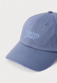 Heledasinine baseballi kork, mis on valmistatud puuvillast ja millel on kumer ääreosa. Eesmisel paneelil on tikitud tekst "tommy jeans". Struktureeritud disain.