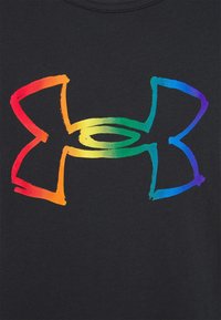 Logo Under Armour avec un style de coups de pinceau bruts en dégradé arc-en-ciel horizontal sur un fond en tissu noir.