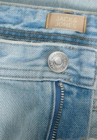 Φωτεινό μπλε τζιν με ασημί κουμπί με την επωνυμία Jack & Jones και μερικώς ορατό φερμουάρ κάτω από τη μέση.