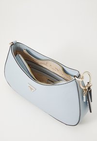 Sac à main structuré bleu clair avec une finition texturée, matériel doré et un accent de logo. Dispose d'une fermeture éclair et de plusieurs compartiments intérieurs.
