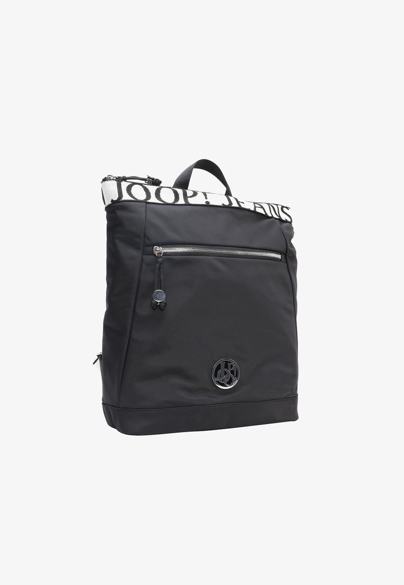 Mochila negra con una tela texturizada, que cuenta con un bolsillo frontal con cremallera, correas ajustables y un parche con logotipo. La banda superior tiene letras en negrita.