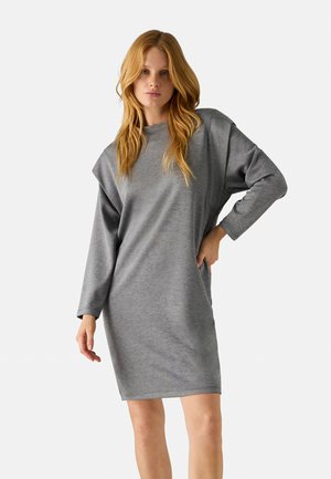 Vestido gris de gran tamaño hecho de una tela suave, con mangas largas y un escote redondo. El diseño incluye un ajuste suelto y relajado.