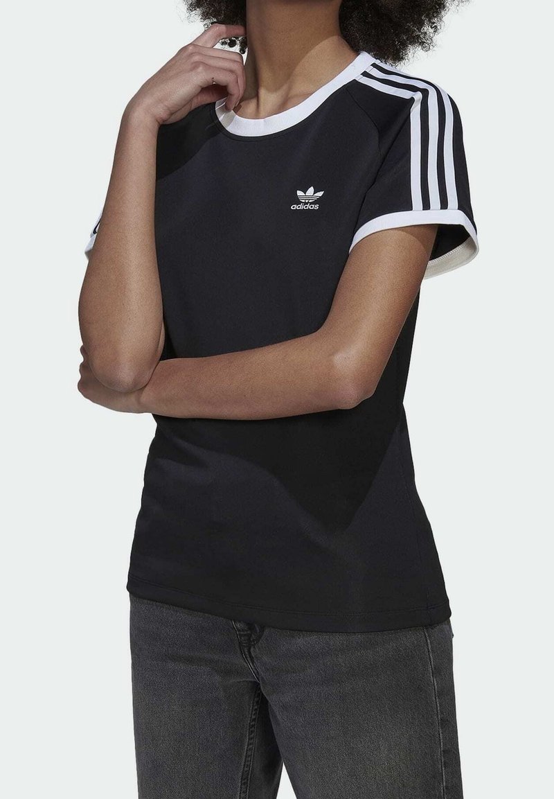 Svart tränings t-shirt med vit krage och tre vita ränder på ärmarna; har en liten vit Adidas-logotyp på bröstet.