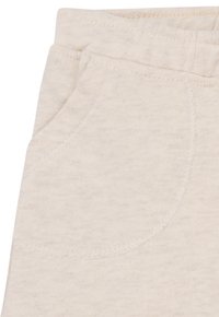 Lichtbeige joggingbroek van zachte stof met een enkele voorkantzak en zichtbare stiksels.