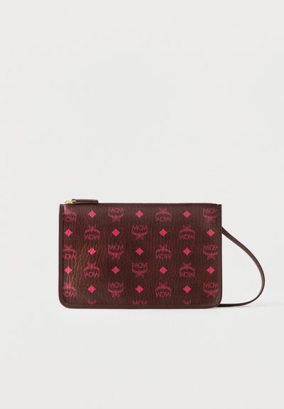Pochette en cuir marron zippée avec logos MCM roses et diamants, équipée d'une sangle pour le poignet sur le côté droit.